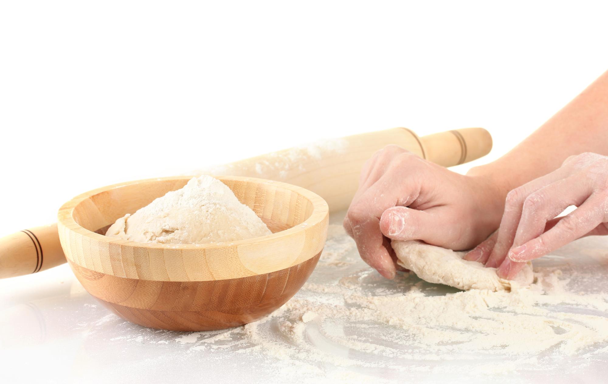 Hands preparing fresh pasta on wooden board